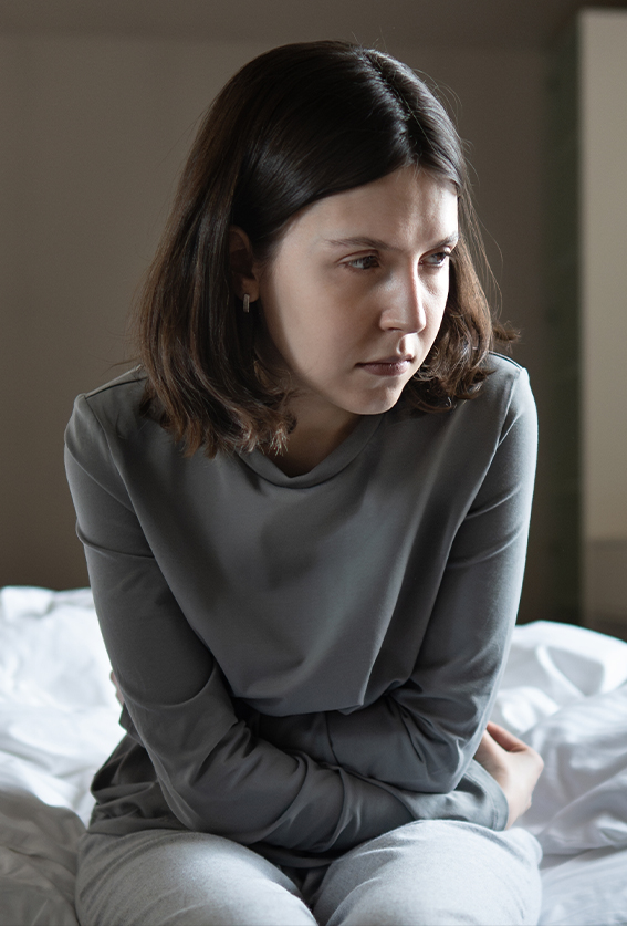A woman sitting on the edge of a bed, held in contemplation